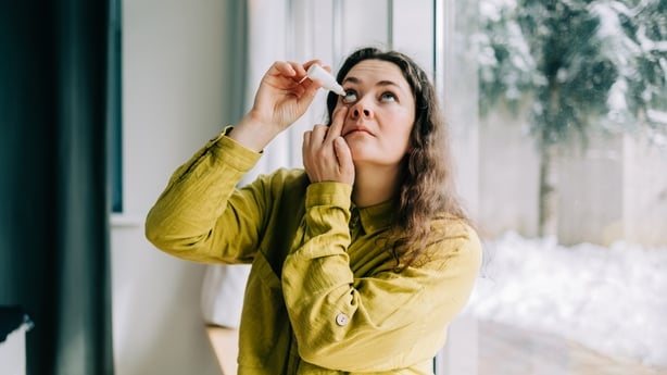 Woman using eye drops at home during winter season