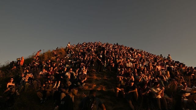 Hundreds of residents and tourists pack the steep, grassy slopes of the historic Krakus Mound in Krakow