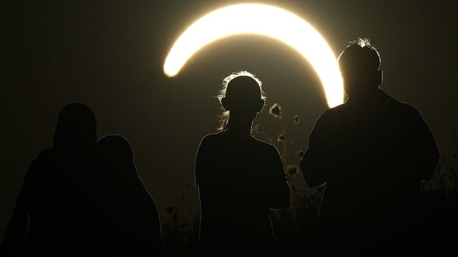 People observe a partial solar eclipse at Northala Fields in London,
