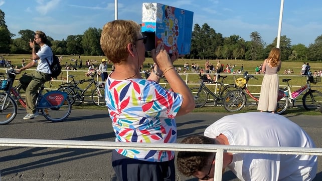 Woman using a homemade viewing device made out of a cereal box joins people gathering in Phoenix Park in Dublin to watch the solar eclipse