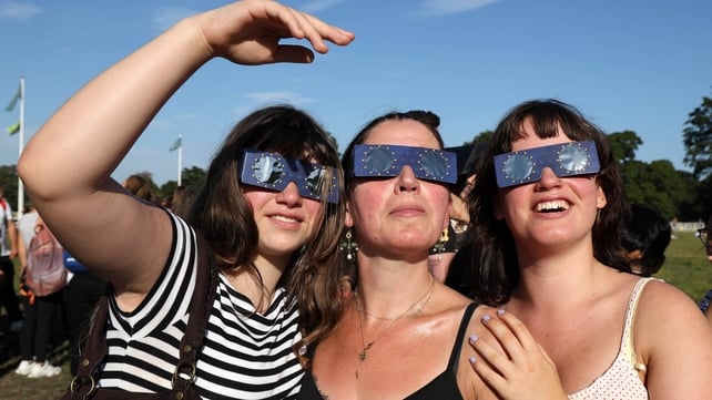 Andrea Caro from Dublin watches the eclipse with her daughters, Iris Currie (12) and Pearl Currie (17) in the Phoenix Park, Dublin