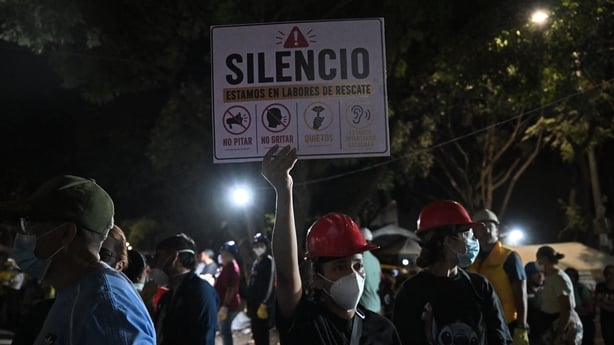 Rescue workers ask for silence as they search for survivors at the site of collapsed buildings after an earthquake in Cali,