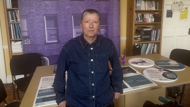 Dola Twomey stands in front of a desk containing sexual assault support materials