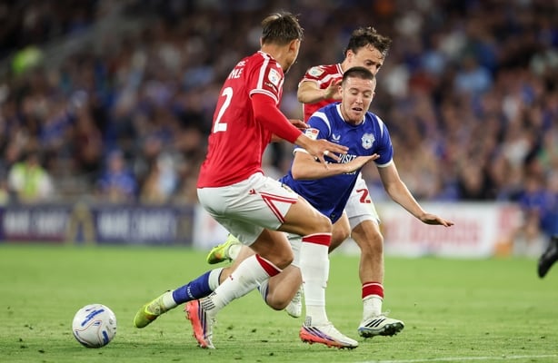 Jack Moylan of Cardiff City is tackled by Callum Doyle of Wrexham and Ollie Rathbone of Wrexham during the Sky Bet Championship 2026/27 match between Cardiff City and Wrexham at Cardiff City Stadium on August 17, 2026 in Cardiff, Wales.
