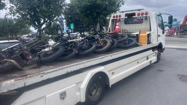 A number of seized electric vehicles are seen on the back of a flatbed truck