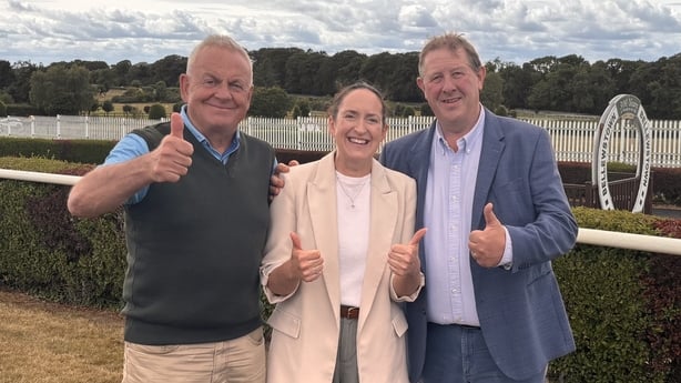 Three representatives of Bellewstown race track standing with thumbs up on the grassy track