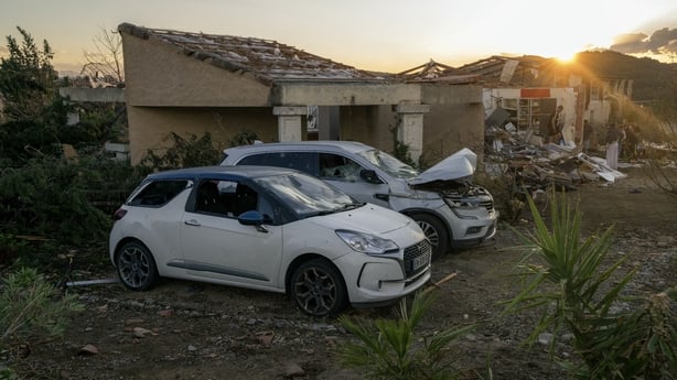 Two damaged cars with damaged buildings in the background