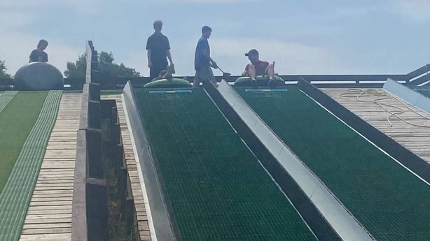 a group of people standing on a green slide