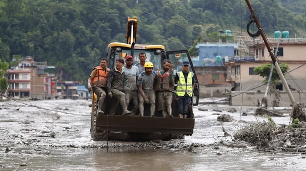 Security personnel rescue people in a bulldozer from buildings that were damaged along the swollen Trishuli River following a massive flash flood triggered by an avalanche of ice and rock in the upper Lhende River on the Tibetan side