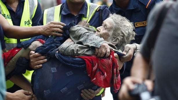 An elderly woman is carried by rescuers