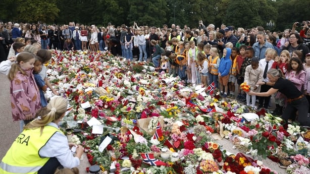 Mourners lay flowers, candles and Norwegian flags as they gather to pay tribute to King Harald of Norway
