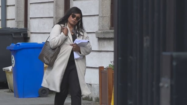 Woman wearing sunglasses walks outside court