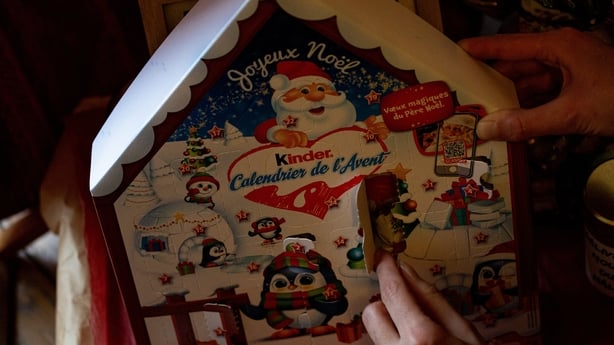 An adult opens a box in his advent calendar and takes out a Kinder chocolate in Paris, France on December 5, 2024. Illustration of Christmas traditions. (Photo by Amaury Cornu / Hans Lucas / Hans Lucas via AFP)