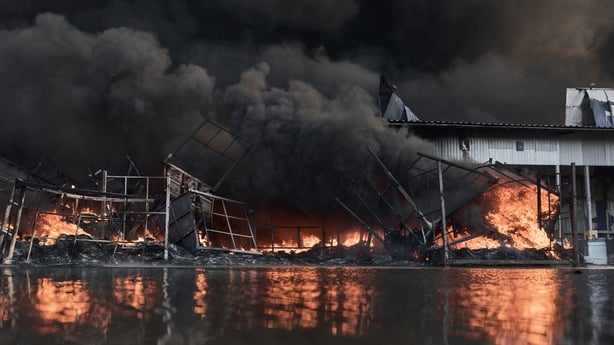 Smoke rises from a fire at a large warehouse storing car tires and wheels following a Russian strike in the Bucha district 