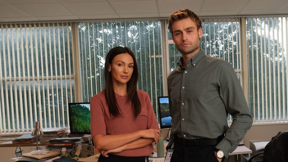 two people standing in an office with computers and paperwork. two people standing in an office with computers and paperwork.