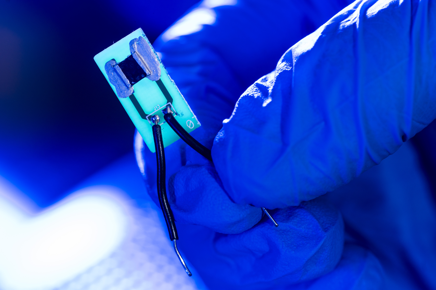 A small device is illuminated against a blue backdrop.