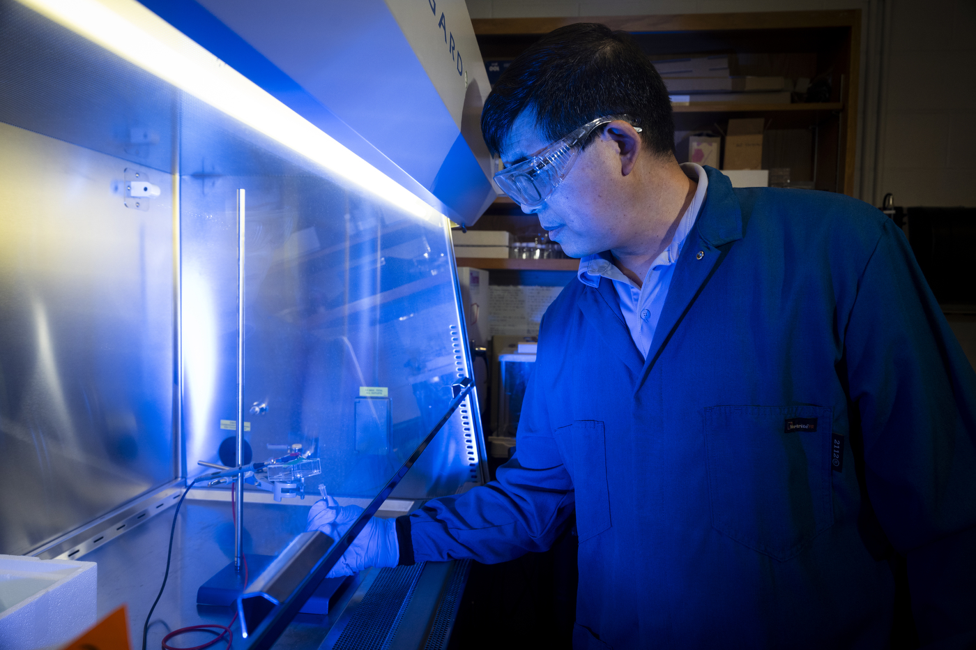 Northeastern professor Nian Sun examines a sensor inside a laboratory testing enclosure.