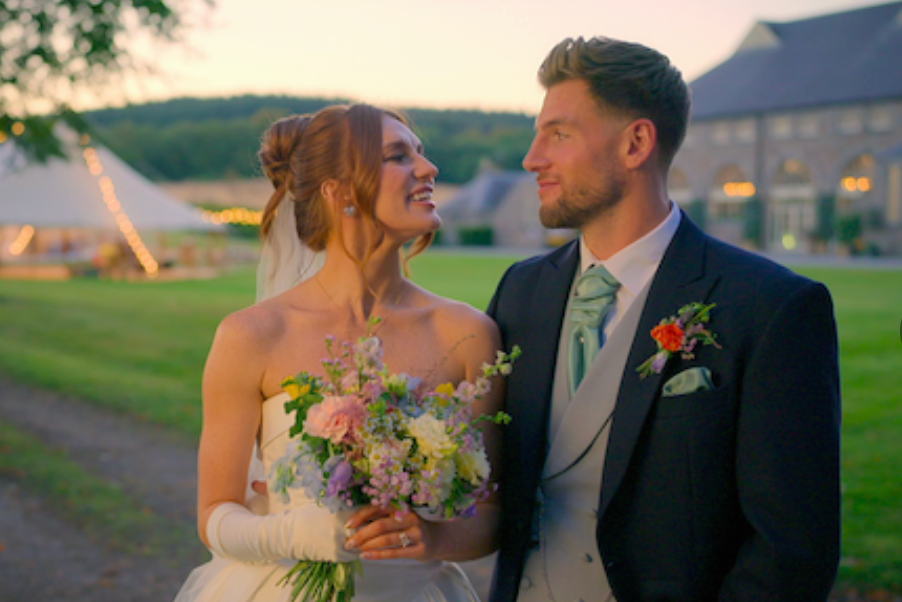 bride and groom smiling at each other in garden setting with lights. bride and groom smiling at each other in garden setting with lights.