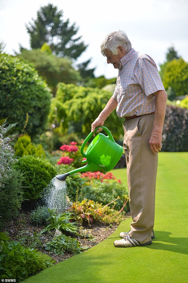 Stuart pictured in 2024 watering his garden, which was previously named 'Britain's Best Lawn'