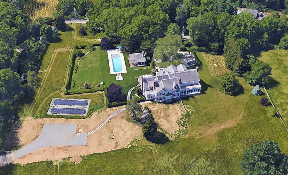 Aerial view of a large house with a pool, yard, and solar panels.