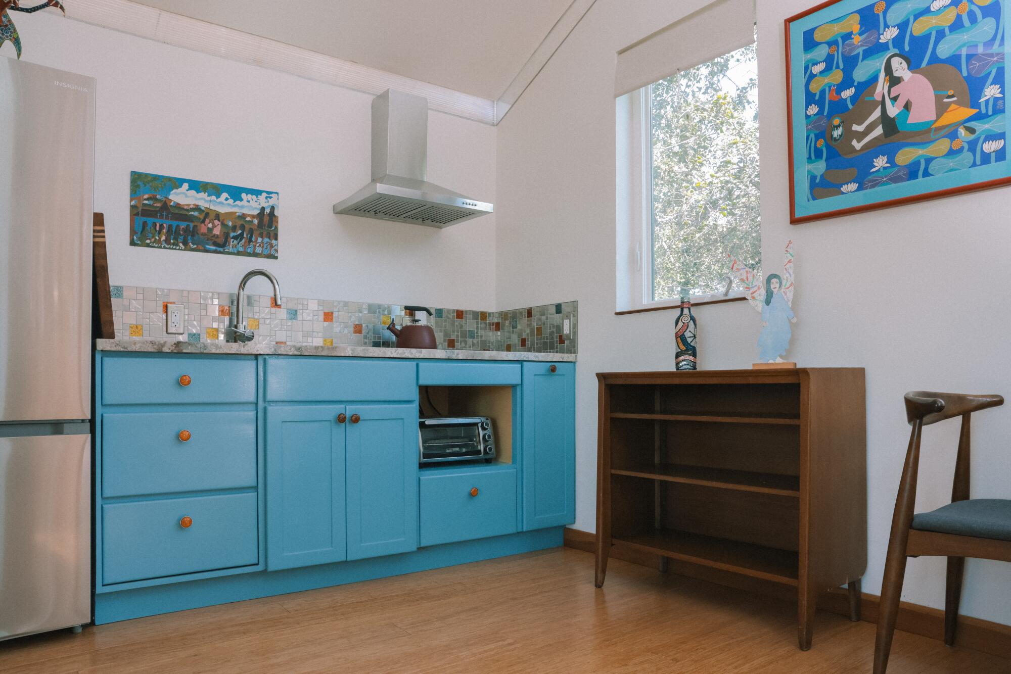 A kitchen with blue cabinets and colorful tile.
