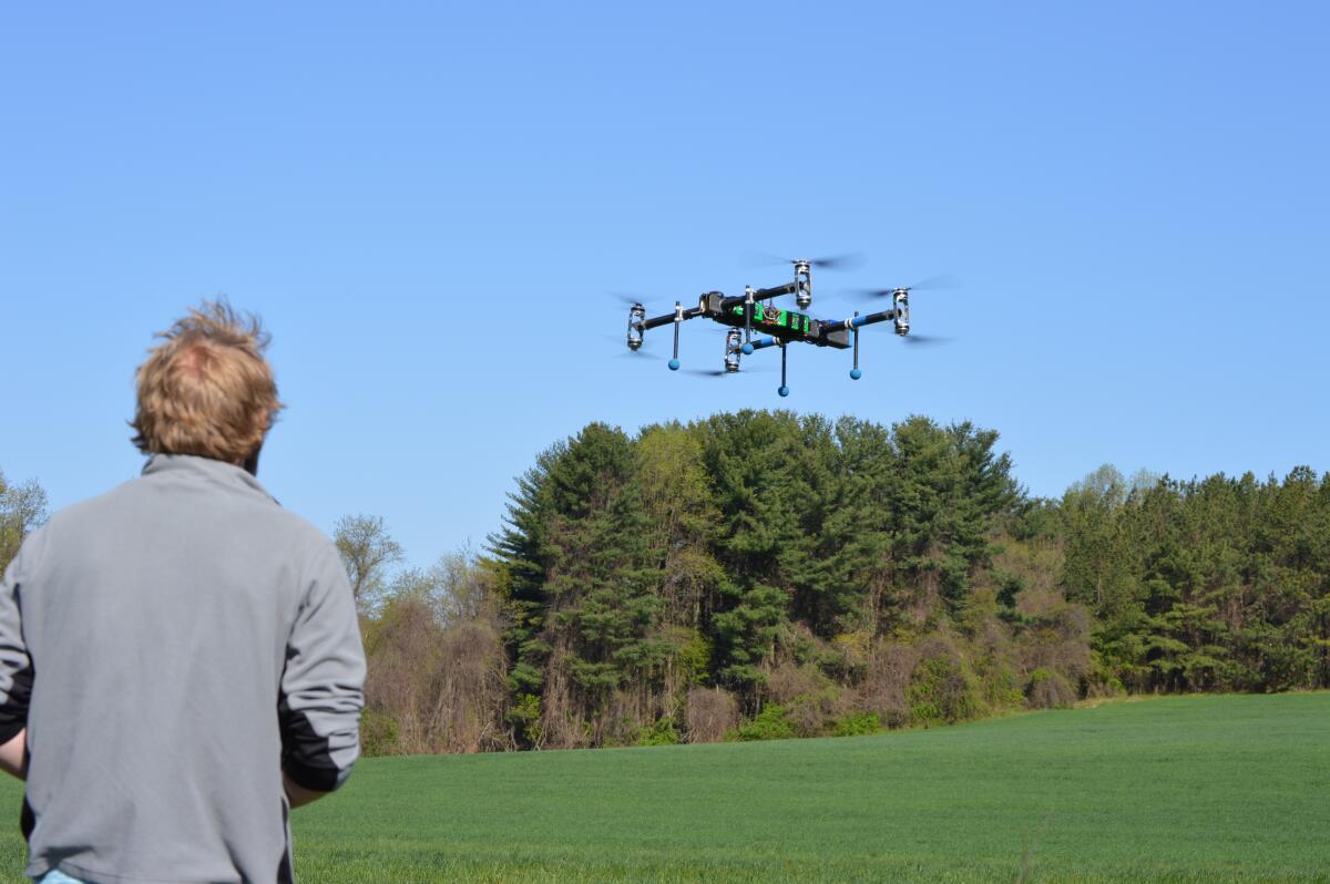 A man operates a drone in a grassy field. 