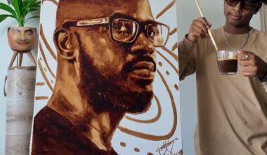 Ricollin Moodley standing next to his painting of Black Coffee made with coffee.