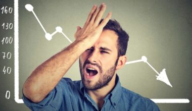 A man stands in front of a chart with an arrow going down and slaps his forehead in frustration.
