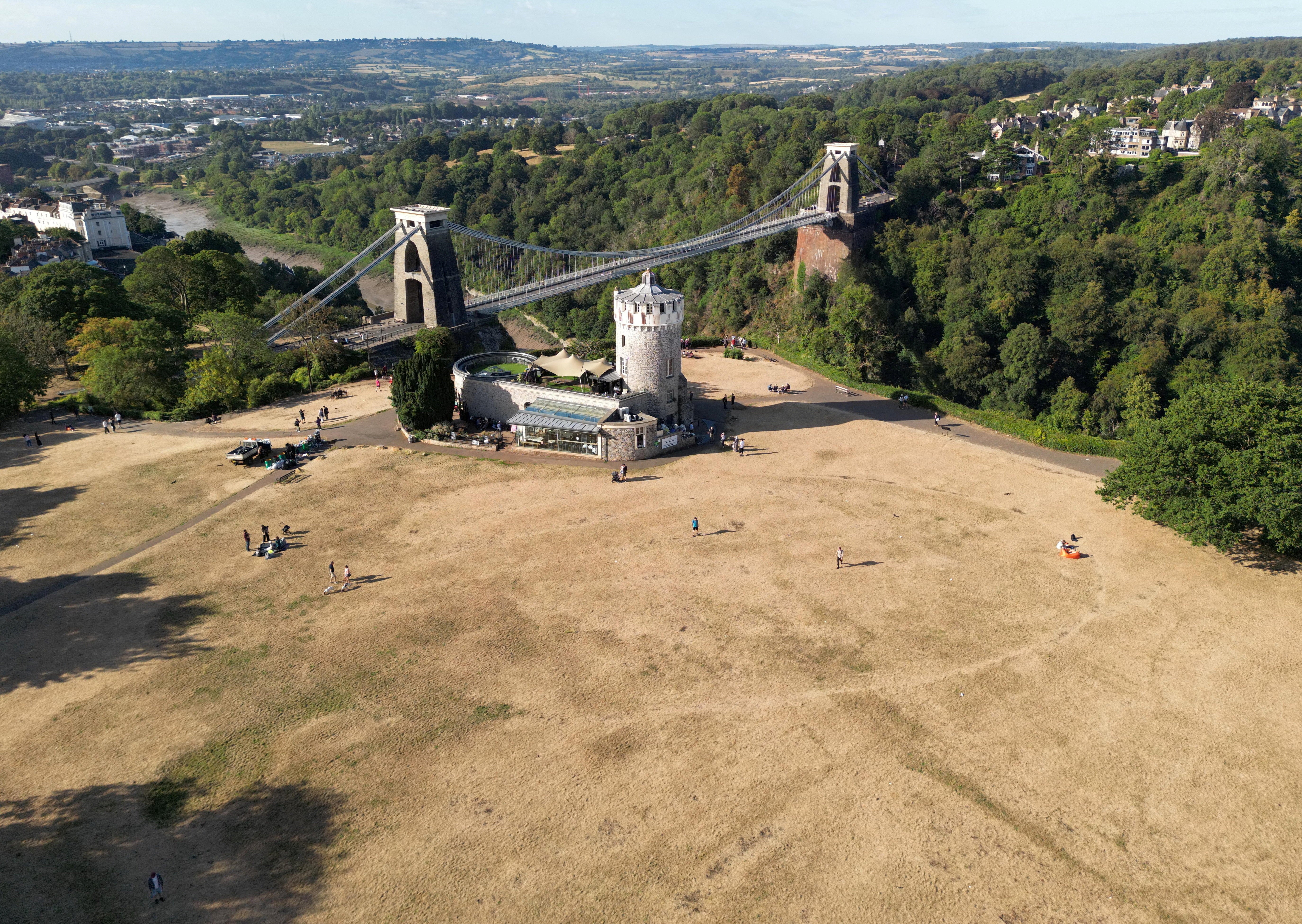 A drone view shows parched parkland around the Clifton Observatory, with Clifton Suspension Bridge behind