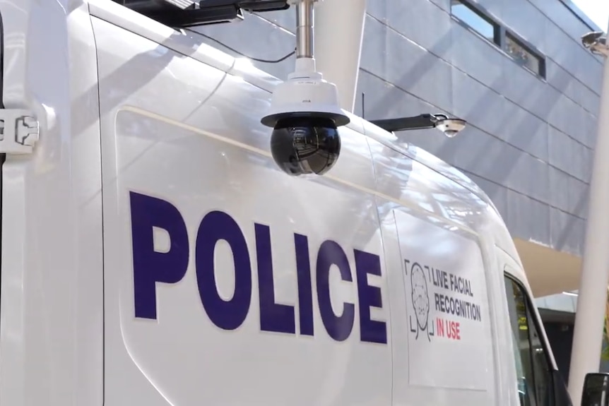A spherical black camera sits atop a white police van.