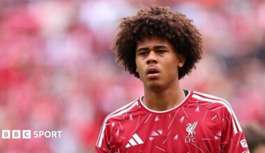 Ifeanyi Ndukwe is looking on in a red Liverpool shirt