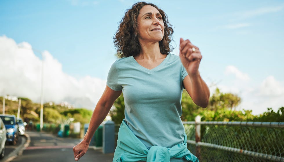 Smiling mature woman out for a power walk in summer Smiling mature woman out for a power walk in summer