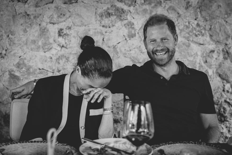 A couple laughing and enjoying each other’s company at a table, with drinks and food visible.