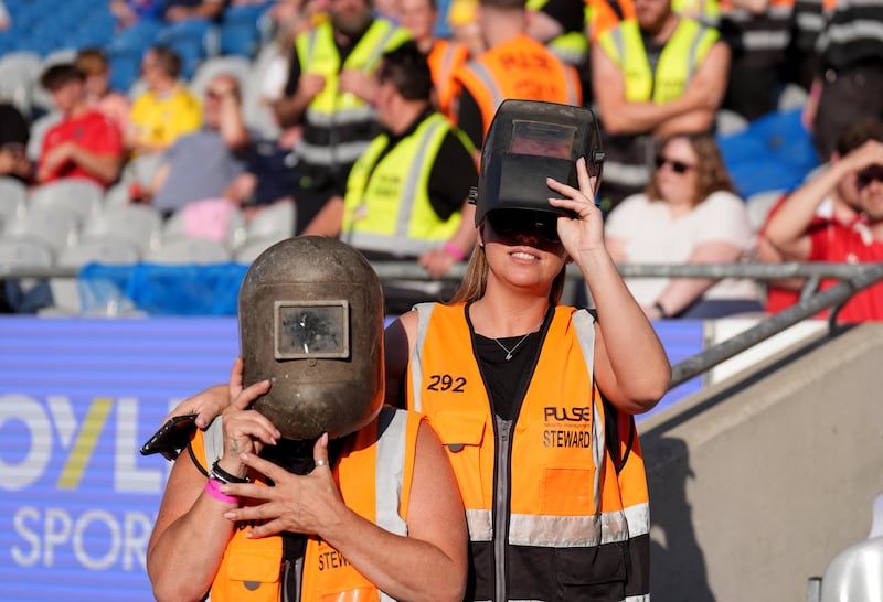 Stewards wear welding helmets to watch the solar eclipse ahead of the Manchester United v Leeds soccer match in Croke Park. Photograph: Niall Carson/PA Wire