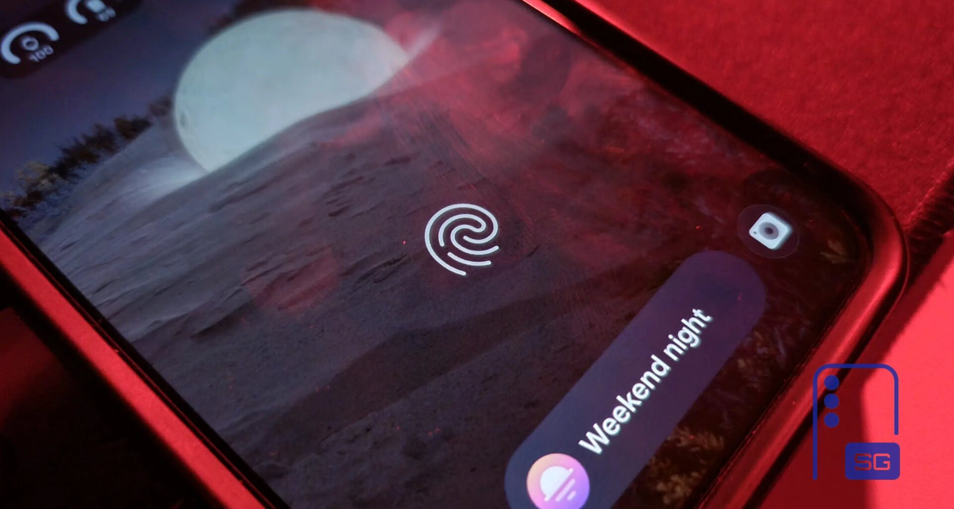 Close-up of a Galaxy phone lock screen showing the under-display fingerprint icon over a moonlit landscape wallpaper, with a Weekend night mode chip beside it