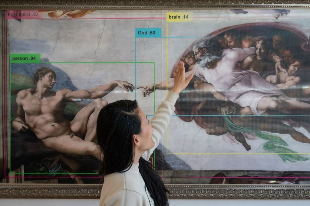 Hand of iGod: An artist stands in front of an artwork at an exhibition aimed at helping visitors think about the potential dangers of artificial intelligence
