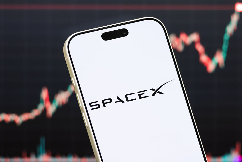 A phone with a SpaceX logo hovers in front of a fluctuating stock graph.
