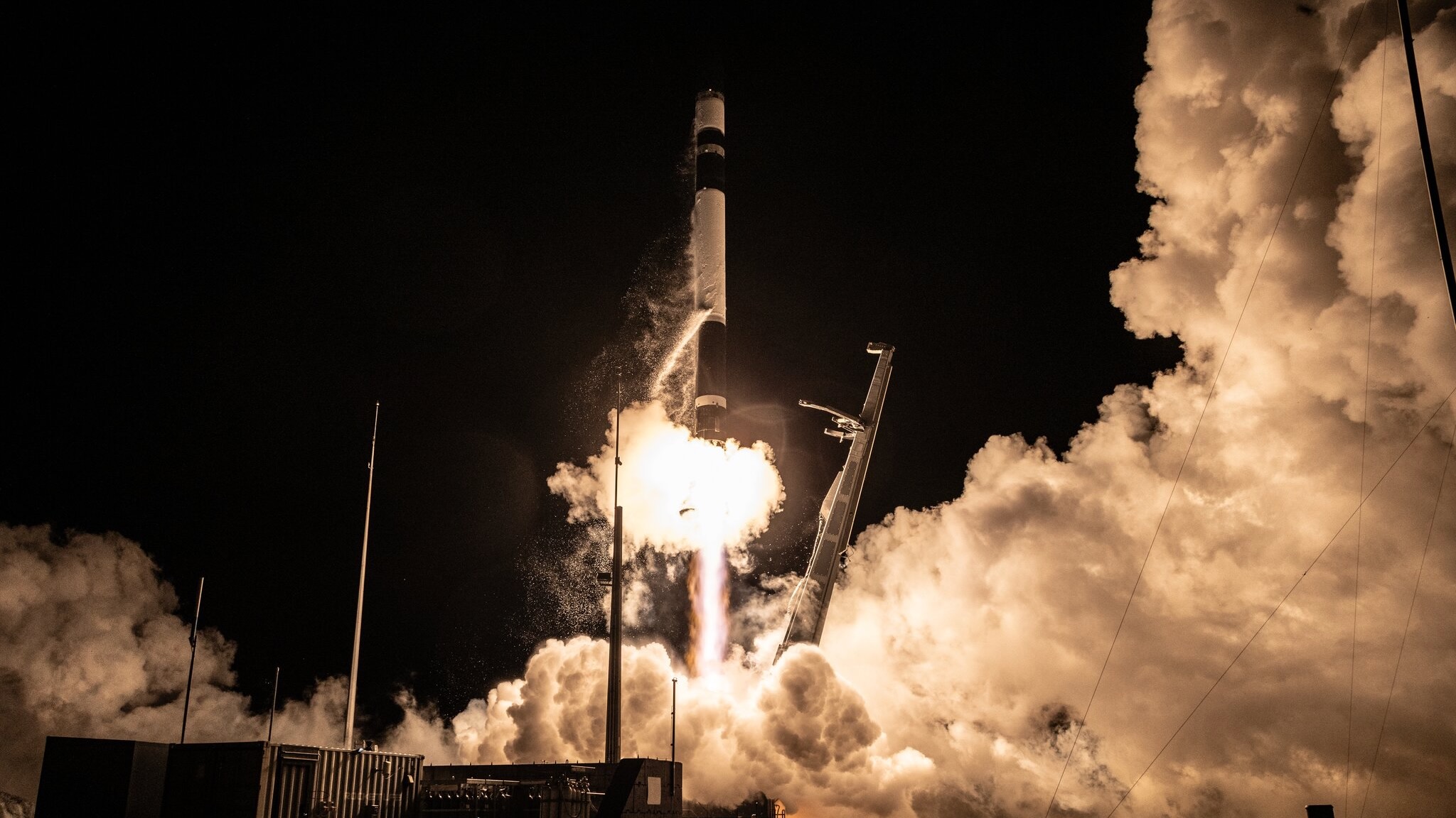 a black-and-white rocket launches into a night sky