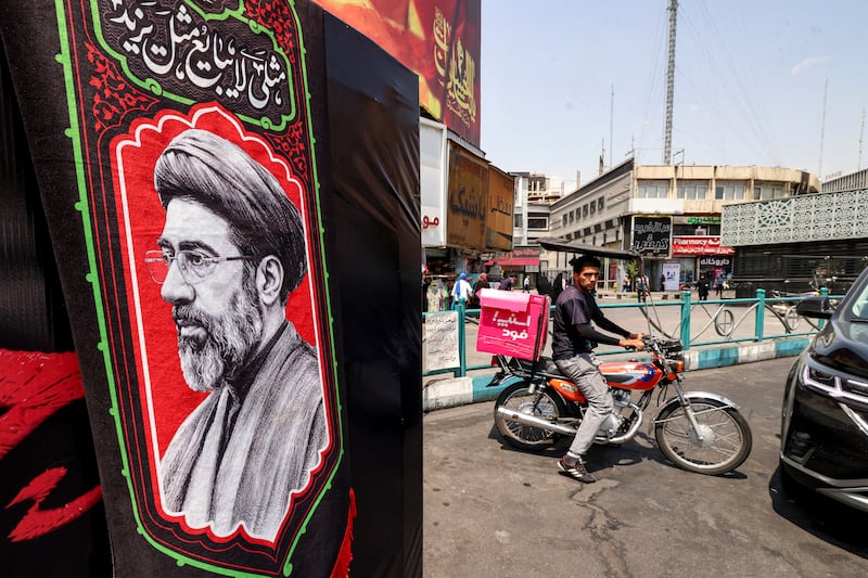 A delivery person rides a motorcycle near an image of Iran's supreme leader Mojtaba Khamenei at Valiasr Square in central Tehran on Saturday. Photograph: Atta Kenare/AFP via Getty Images