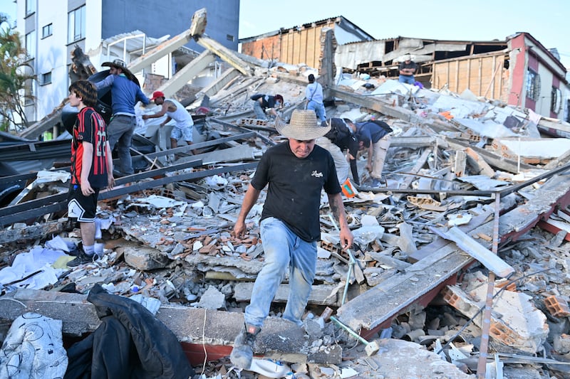People and rescuers search for victims in the debris of a collapsed building in Pereira, Colombia. Photograph: Gabriel Aponte/Getty Images