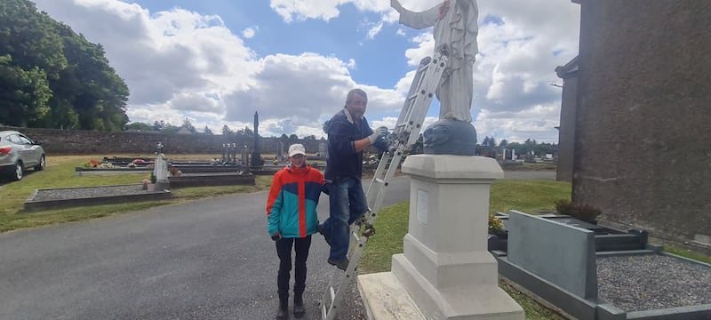 Jemima Ottman and Colman Kirby help with painting a statue on the church grounds
