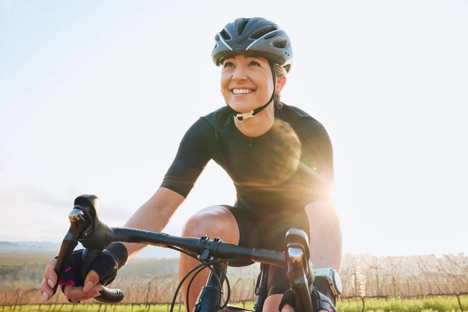 File photo: a happy female cyclist wears a helmet as she pedals outdoors.