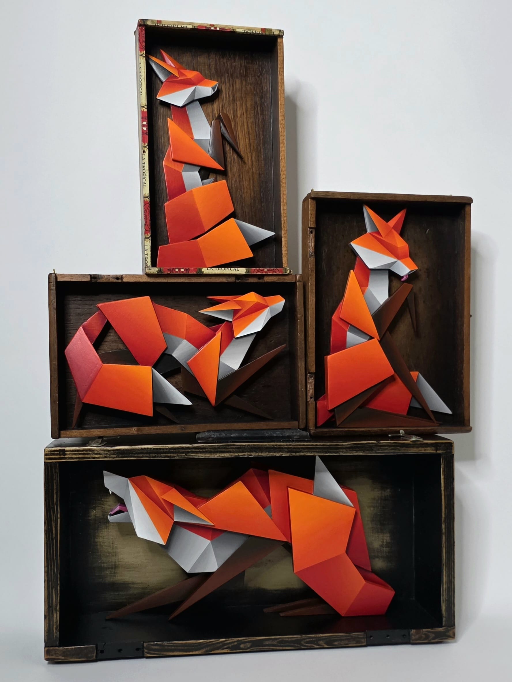four sculptural, geometric foxes installed inside of shadow boxes
