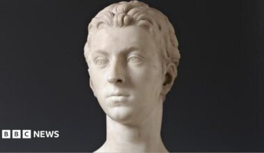The bust is made from marble and shows the head of a young man, Sir John Gordon. The sculpture is photographed against a black background.