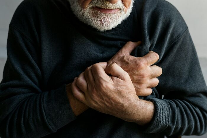 An elderly man clutches his chest, suggesting discomfort or pain, relevant to medical field workers insights.