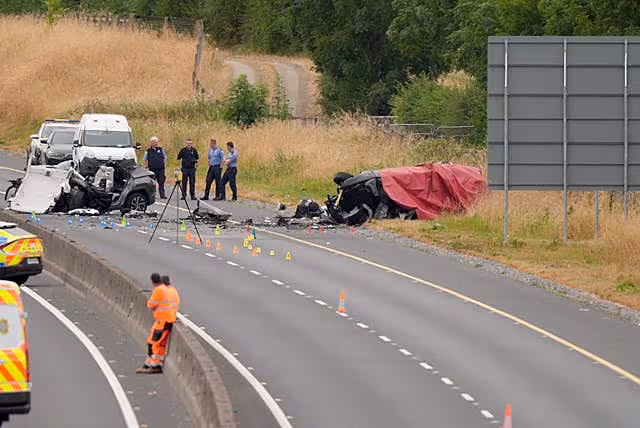 A red blanket draped over the remains of a badly damaged car