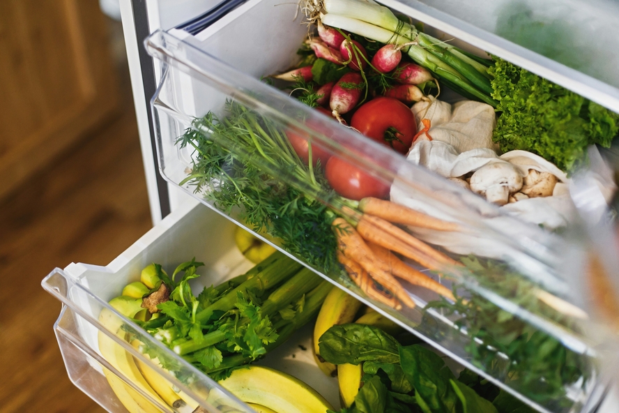 Image of an open refrigerator with two clear open drawers showcasing lots of fresh fruit and vegetables.