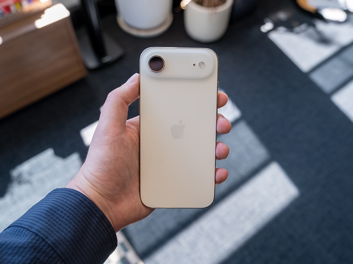 iPhone 17 Air in white held in hand, showing rear camera and Apple logo in a sunlit room.