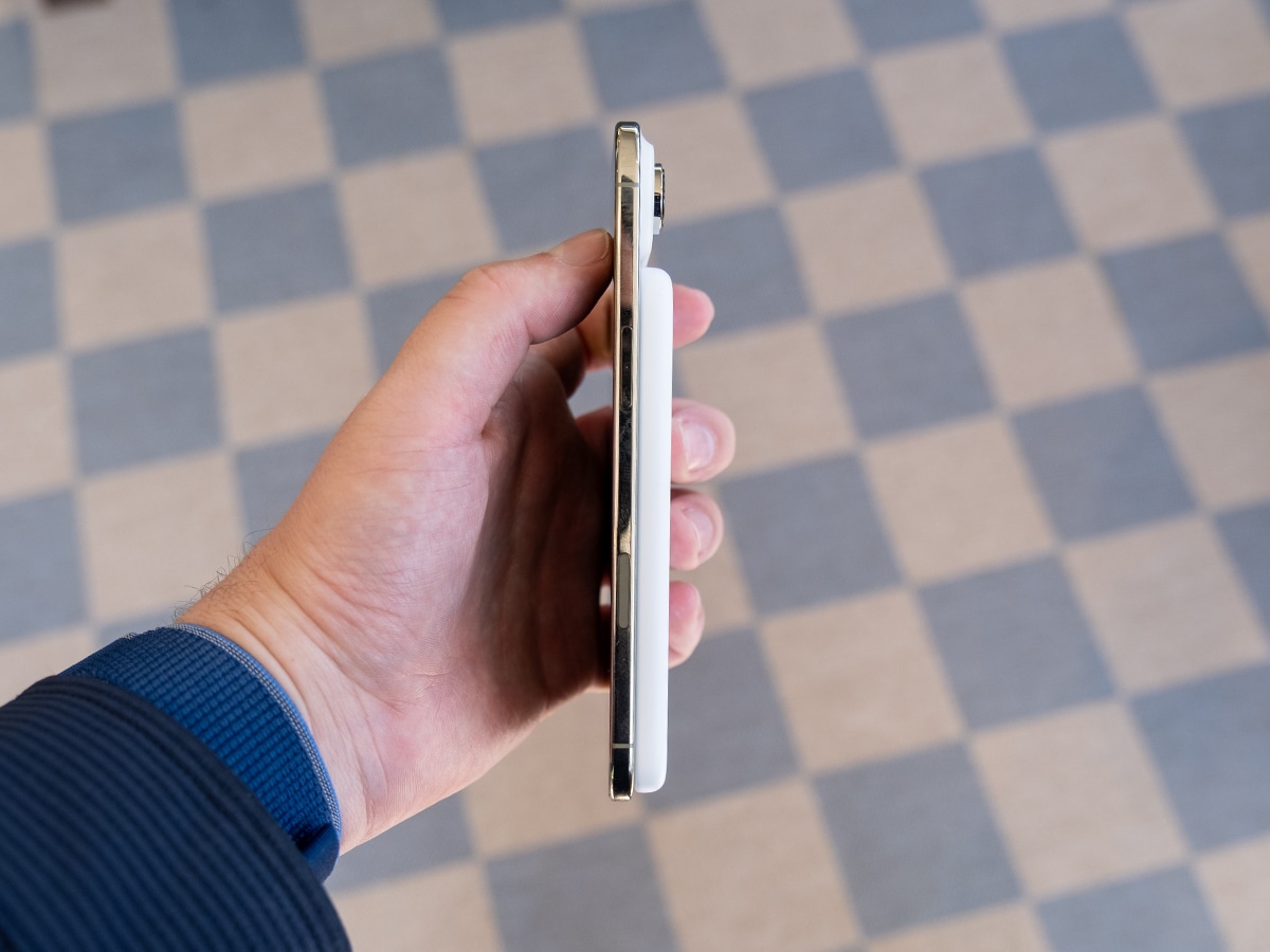iPhone 17 Air in white held sideways showing slim profile against checkered floor background.