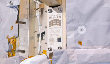 A close-up view of NASA's Nancy Grace Roman Space Telescope shows a commemorative plaque with writing on it, as well as an illustration of Roman, and a memory card.